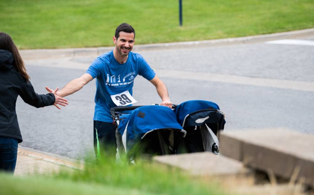 Alex Priebe pushing a stroller and excitedly high-fiving a colleague during the race